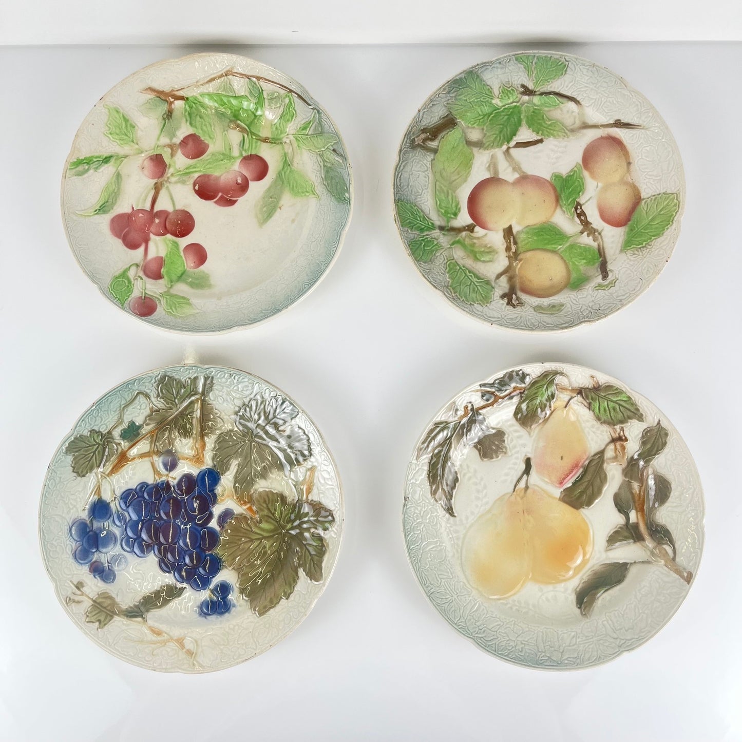 Set of 4 KG St Clément barbotine fruit plates (cherry, mirabelle plum, grape, pear), late 19th-early 20th century