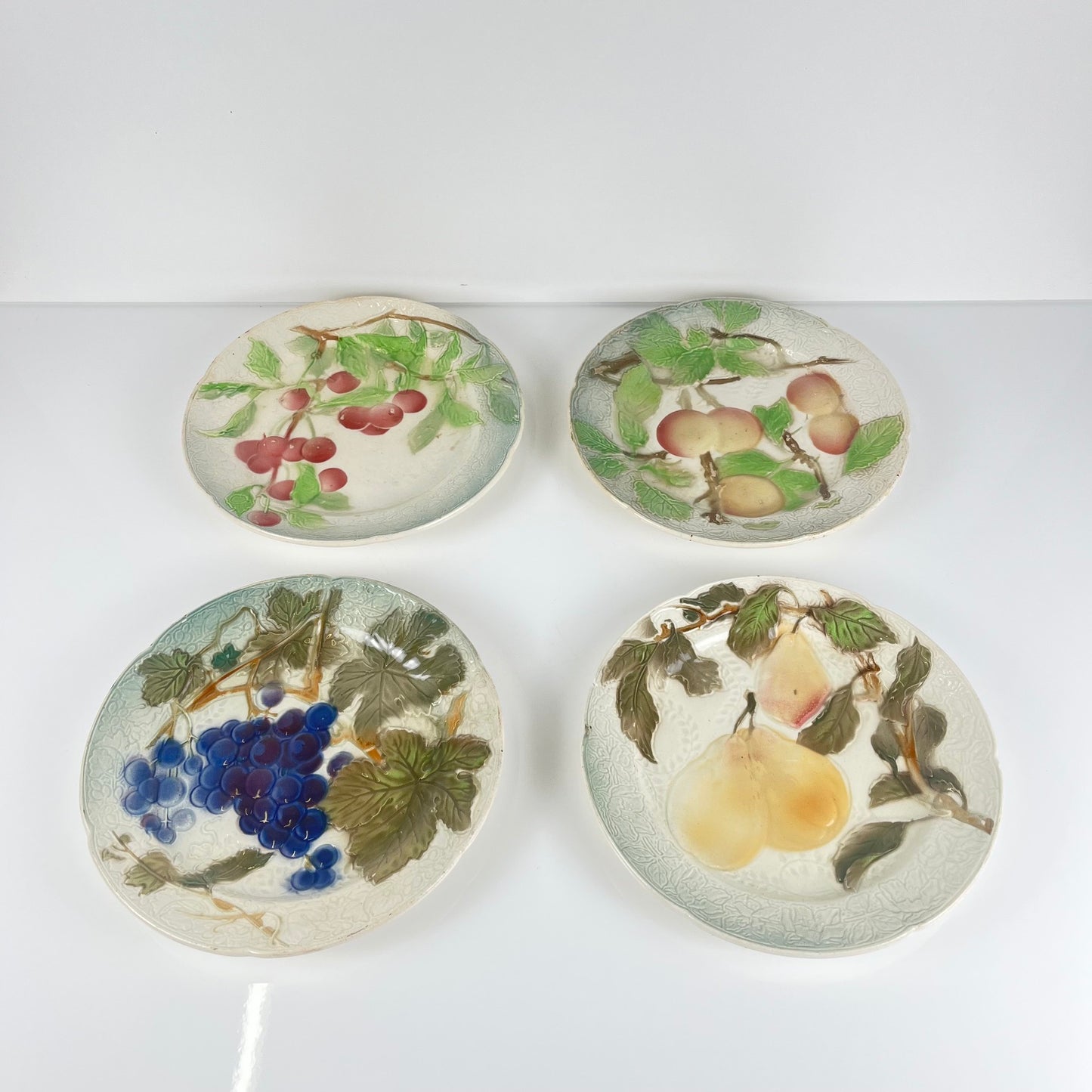 Set of 4 KG St Clément barbotine fruit plates (cherry, mirabelle plum, grape, pear), late 19th-early 20th century